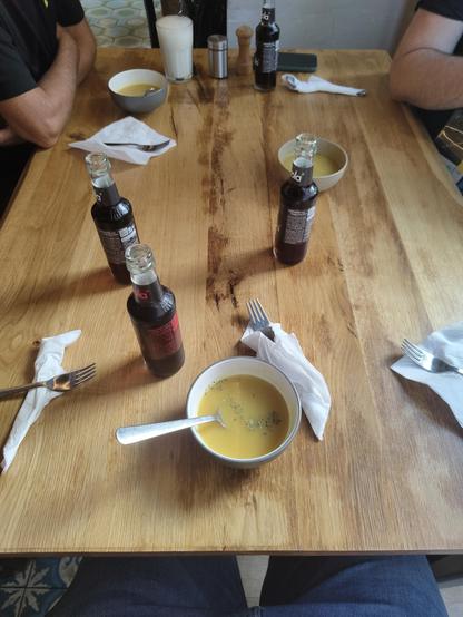Restaurant table with drinks, soups and cutlery